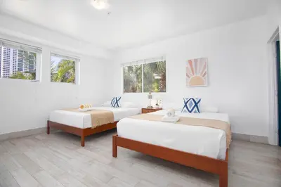 two beds in a white room with two windows at Boutique Apartments SoBe in Miami Beach