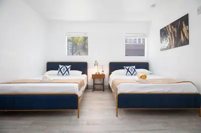 two beds in a room with white walls at Boutique Apartments SoBe in Miami Beach