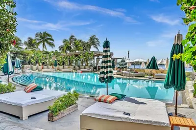 a pool at a resort with two beds and umbrellas at Brand New Mondrian - Miami Beach Waterfront Condo in Miami Beach
