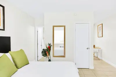 a white bedroom with a bed and a mirror at New Mimo 8 New -Walkable - Smart TV - Nespresso - Free Parking in Miami