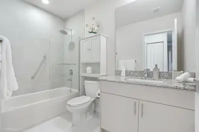 a white bathroom with a toilet and a sink at Beachside Bliss, 1BR Condo with Pool at Dania Beach in Dania Beach