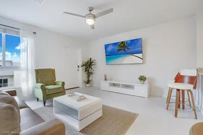 a white living room with a couch and a table at Beachside Bliss, 1BR Condo with Pool at Dania Beach in Dania Beach