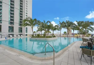 a large swimming pool with palm trees in a resort at Sunlit 1BR Condo In Downtown Miami in Miami