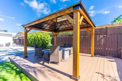 a wooden pergola with a table and chairs on a deck at Stunning Tropical Pool House Miami Coconut Grove in Miami