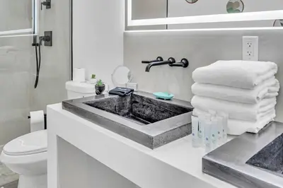 a bathroom with a sink and a toilet and towels at Stunning Tropical Pool House North Miami in Gold Coast Heliport