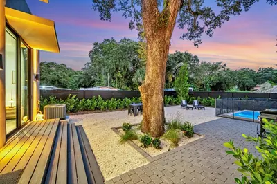 a patio with a tree and benches next to a house at Stunning Tropical Pool House North Miami in Gold Coast Heliport