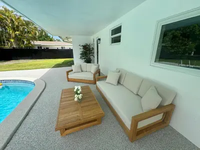 a living room with a couch and a table next to a pool at Chic-ness Oasis NOW HEATED POOL ! in Cutler Bay
