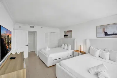 a white bedroom with two beds and a couch at Modern Ocean Escape Stylish 2BR Condo with Resort Amenities Pools Sauna and Gym 1417 in Miami Beach