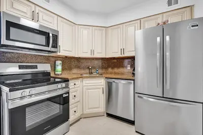 a kitchen with white cabinets and stainless steel appliances at Modern Ocean Escape Stylish 2BR Condo with Resort Amenities Pools Sauna and Gym 1417 in Miami Beach