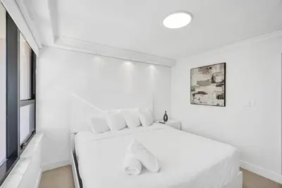 a white bedroom with a white bed with white pillows at Modern Ocean Escape Stylish 2BR Condo with Resort Amenities Pools Sauna and Gym 1417 in Miami Beach