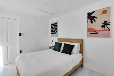 a bedroom with a bed with white sheets and blue pillows at Relax & Fun Hollywood Private Pool | Arcade Game in Hollywood