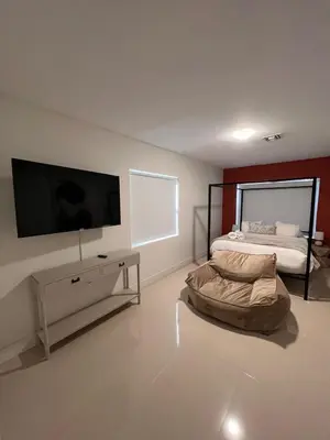 a living room with a bed and a flat screen tv at Lux Retreat with Pool Near Beach in Fort Lauderdale