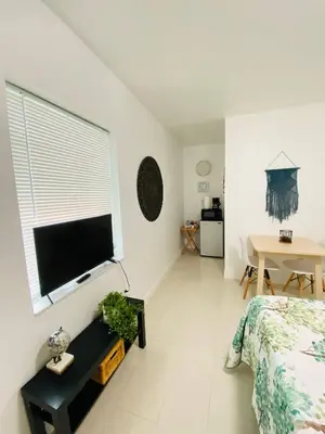 a bedroom with a bed and a flat screen tv at Walk to Calle 8 - Authentic Cuban Experience in Miami