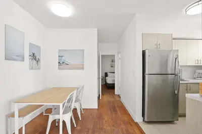 a kitchen with a table and a stainless steel refrigerator at Modern Miami Beach Apt King & Sofa Bed Comfort in Miami Beach