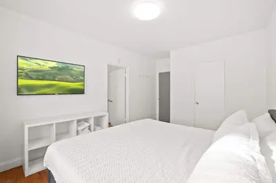 a white bedroom with a bed and a tv on the wall at Modern Miami Beach Apt King & Sofa Bed Comfort in Miami Beach