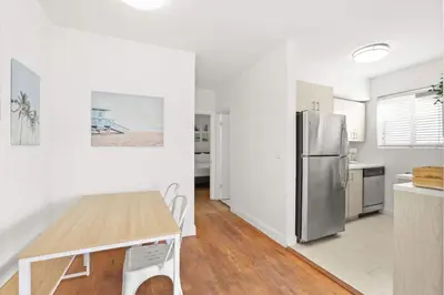 a kitchen with a table and a stainless steel refrigerator at Modern Miami Beach Apt King & Sofa Bed Comfort in Miami Beach