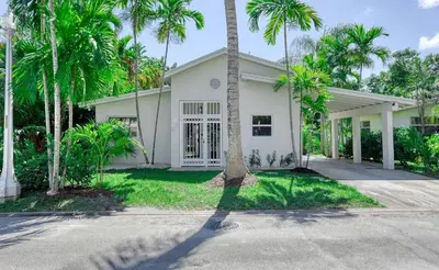 a white house with palm trees in front of it at Palace at the Gables in Miami