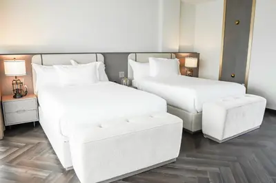 two beds with white sheets and a bench in a room at Barley House Hotel, Trademark Collection by Wyndham in Fort Lauderdale