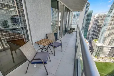 a balcony with chairs and a table on a building at Sun, Style and Skyline Modern Icon Brickell 2BR in Miami