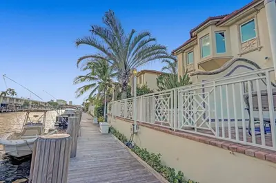 a house with a balcony and a boat on the water at Massive waterfront home with pool in North Miami Beach