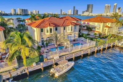 a boat on the water in front of some houses at Massive waterfront home with pool in North Miami Beach
