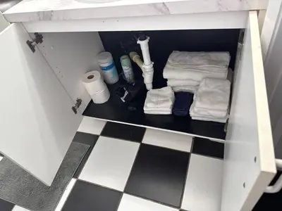 a cabinet with towels and toiletries on a checkered floor at Walk to South Beach in Miami Beach