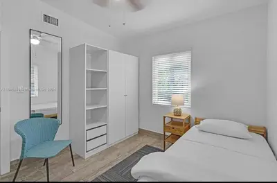 a bedroom with a bed and a desk and a mirror at Avocado House A Coconut Grove Bungalow in Miami