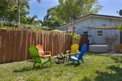 four colorful chairs in a yard next to a fence at 10 min to Las Olas and Beach WD 2 Bed in Fort Lauderdale