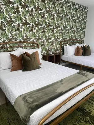 two beds in a room with a wall with palm trees at Tropical Oasis in Pembroke Pines