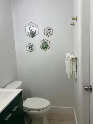 a bathroom with a toilet and some pictures on the wall at Tropical Oasis in Pembroke Pines