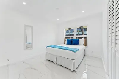 a white bedroom with a bed with blue pillows at Family Splash Escape in Fort Lauderdale