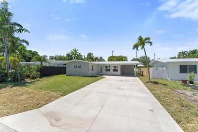 a house with a driveway and palm trees at Family Splash Escape in Fort Lauderdale
