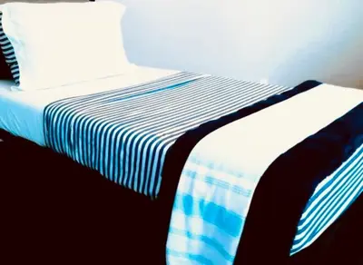 a bed with a blue and white striped sheets and a pillow at House FLL airport in Fort Lauderdale