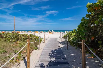 a boardwalk leading to the beach with the ocean in the background at SeaStays- South Beach Apartments in Miami Beach