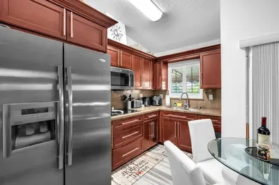 a kitchen with wooden cabinets and a stainless steel refrigerator at Lime Haus lime - Your Family Stay in Miami Awaits in Tamiami
