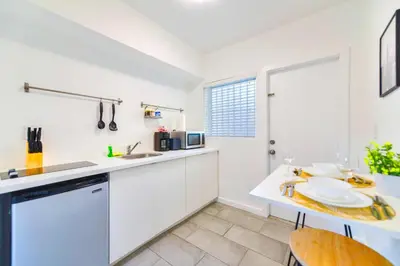 a kitchen with white cabinets and a table and a sink at Charming Studio in a Beautiful Neighborhood Setting in Miami