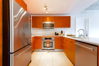 a kitchen with wooden cabinets and a stainless steel refrigerator at Stylish Midtown Miami Condo - Pool & Prime Location in Miami