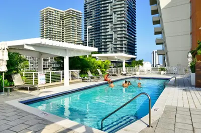 a pool with people in it with tall buildings at Stylish Midtown Miami Condo - Pool & Prime Location in Miami