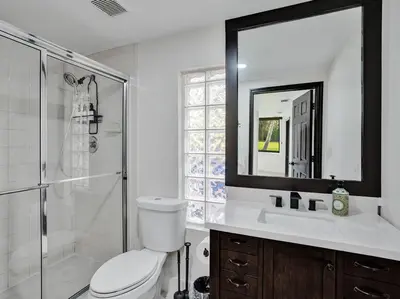 a bathroom with a toilet and a shower and a mirror at Villa Riverland in Fort Lauderdale