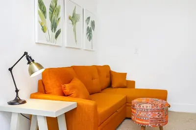 an orange couch in a living room with a table at Alton Rd By At Mine Hospitality in Miami Beach