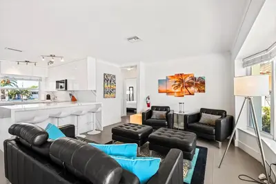 a living room with black leather furniture and a kitchen at Waterfront Oasis with Pool, Sunset Views and Dock in Fort Lauderdale