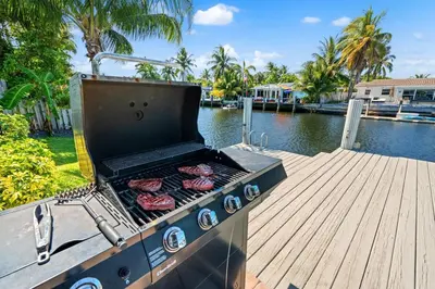 a grill on a dock with hamburgers on it at Waterfront Oasis with Pool, Sunset Views and Dock in Fort Lauderdale