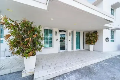 a white house with two potted plants on a patio at Alamo Hotel in Miami Beach