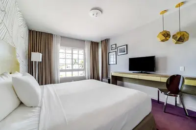 a hotel room with a bed and a desk with a television at Alamo Hotel in Miami Beach