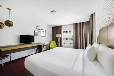 a hotel room with a large bed and a desk at Alamo Hotel in Miami Beach
