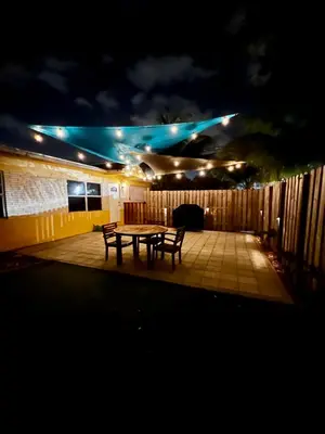 a patio with a table and two benches at night at Fort Lauderdale Florida Beach Vibe Hangout in Fort Lauderdale