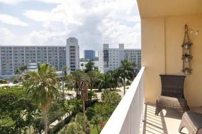 a balcony with chairs and palm trees and buildings at Tiny Tower Treasure - Sleeps 5 & Soaks Sun in Sunny Isles Beach