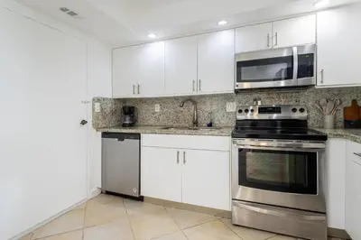 a kitchen with stainless steel appliances and white cabinets at Tiny Tower Treasure - Sleeps 5 & Soaks Sun in Sunny Isles Beach