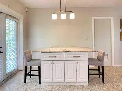 a kitchen with a white island with two chairs at 2 Bedroom Cozy House Near Barry University in Miami
