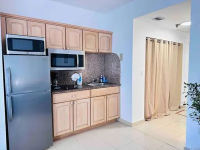 a kitchen with a stainless steel refrigerator and wooden cabinets at Right on the beach, Ocean Drive Secured Condo in Miami Beach